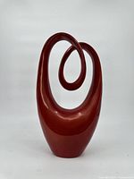 Front view of the red abstract decorative sculpture with a smooth, glossy finish and continuous loop design.