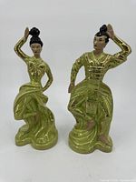 Front view of two glazed green dressed Asian dancer ceramic figurines showing detailed poses and attire.