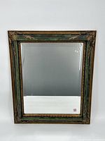 Full view of the rectangular mirror with green and gold gilt ornate frame against a white background, showing the overall appearance and condition.