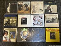Photo of 12 vinyl records arranged in a grid, showing front album sleeves from various artists.