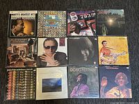 Photo of all 12 vinyl record covers laid out, showing artists and album titles.