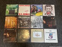 12 vinyl records laid out on carpet, showing front covers clearly