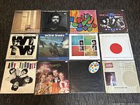 Top view of 12 vinyl records arranged in 3 rows of 4, showing front cover artwork and sleeves for each record