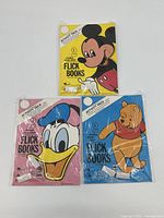 Three Disney comic flick books in original plastic packaging, featuring Mickey Mouse, Donald Duck, and Winnie the Pooh on the covers.