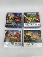 Four boxed 1000-piece jigsaw puzzles from Buffalo Games laid out side by side showing cover artwork and brand logos.