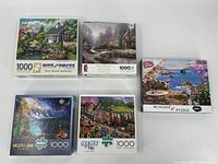 Five 1000 piece puzzle boxes arranged to show titles and cover art, showcasing variety of scenic images.