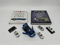 Lot with 8 toy cars including a blue pickup truck with open doors and hood and two books about cars