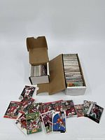 Two open cardboard boxes filled with sports trading cards spread out and stacked showing football player cards.