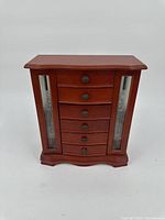 Front view of the wooden jewelry organizer box, closed, showing six drawers and two etched glass side panels.