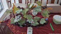 Full view of the carved jade grapevine tree on a wooden base with jade grape clusters and wood bird