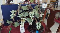 Full view of carved jade tree including green grape clusters and wooden base