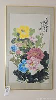 Framed Chinese watercolor painting showing detailed colorful peonies and leaves.
