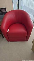 Front view of red leather Natuzzi club chair showing rounded back and seat cushion.