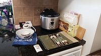 Countertop with Oster rice cooker, ceramic bowls, soy sauce dish, cloth placemats, and boxed sushi supplies visible in the back