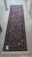 Full view of the long floor runner rug with floral pattern on burgundy background, showing overall design and shape.