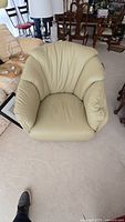Front view of beige faux leather swivel chair showing padded seat and backrest