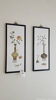 Two framed botanical paintings hanging on a wall, showing overall artwork and frames.