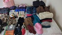 A wide photo showing an assortment of women's outerwear, gloves, hats, scarves, and other accessories arranged on a white surface.