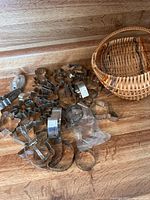Photo showing multiple vintage metal cookie cutters in varied shapes arranged on a wooden surface next to a small wicker basket.