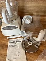 Photo showing the Black & Decker Power Pro II main food processor unit, mixing bowl with handle, lid, citrus juicer, egg separator, slicing and shredding discs, and user manual.