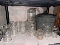 Wide view of all vintage canning jars with enamelware pot at back