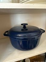 Cobalt blue cast iron Dutch oven with lid on, side view showing handles and knob on lid.