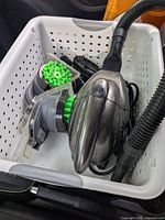 Full view of vacuum and attachments inside a perforated white plastic basket.