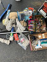 Overview of assorted hardware and tool items including brushes, ropes, cleaning mitt, glue gun, and signage.