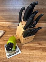 Miracle Blade cutlery set arranged in wooden block with green sharpener on side
