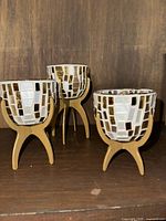 Three Partylite Vienna tealight holders displayed on wooden surface, showing mosaic glass design and wooden tripod bases