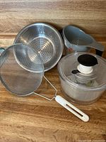 Full view of the set laid out on wooden surface showing the salad spinner, strainers, colander, and mesh strainer.