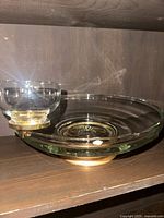 Photo of the full chip and dip set showing the large glass chip dish with brass base and the attached smaller glass dip bowl with brass mount.