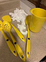 Yellow kitchen utensil set with one yellow pitcher-style holder and white painted Syroco cornucopia wall hanging.