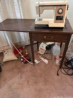 Fully set up vintage Kenmore Model 158 sewing machine on wooden cabinet with fold-out extension leaf, power cord visible under cabinet.