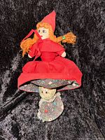 Photo of the vintage reversible Little Red Riding Hood doll showing the Little Red Riding Hood face with red dress and yarn hair over dark black fabric background.