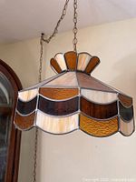 Side angled view of vintage stained glass slag glass swag lamp shade hanging from ceiling chain.