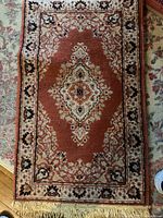 Close-up image showing the rose colored Kirman Open Ground design with central medallion and floral borders on a smaller rug.