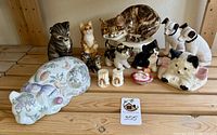 Front view of entire collection showing 12 cats and 2 dogs unboxed on wooden surface