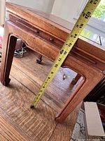 Side view showing table height measurement with tape measure approximately 14 inches tall and the curved leg design