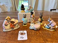 Full view of the 8 Beatrix Potter porcelain figurines displayed on wooden table, showing characters and arrangement.