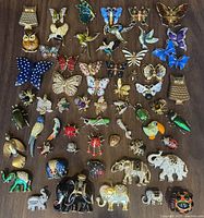 Top view of entire lot showing a colorful collection of animal and insect brooches laid out on a wooden surface.