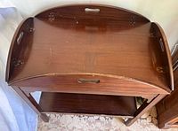 Top angled view showing the drop-leaf sides folded up, oval integrated top with three cut-out handles, and visible hinges for leaves.