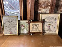 Four samplers on wood floor: Floral Green Ground Needlepoint, Friendship Is a Sheltering Tree Sampler, Rain Rain Go Away Sampler with alphabet and verse by Godmother Dede, gilt framed