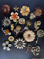 Top down view of all 20 vintage floral brooches arranged flat showing design variety and condition.