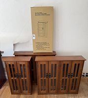Photo showing all four curio cabinets, two large and two small; one small unit boxed and unassembled, other units assembled and standing.