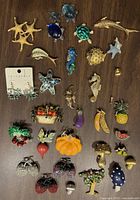 Full view of the lot showing all brooches and earrings, featuring sea creatures, fruits, vegetables, and mushrooms on a wooden surface.