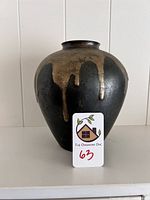 Front view of blackened metal vase showing bronze drip motif and overall shape.