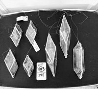 Top-down photo of seven icicle water prisms arranged on a black surface, showing variety of shapes and sizes.