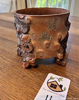 Front side showing calligraphy, impressed makers mark, bark texture, root-like feet and reddish clay color.