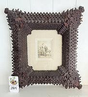 Front view of a tramp art carved wood frame with layered geometric pattern and central mat holding artwork.
